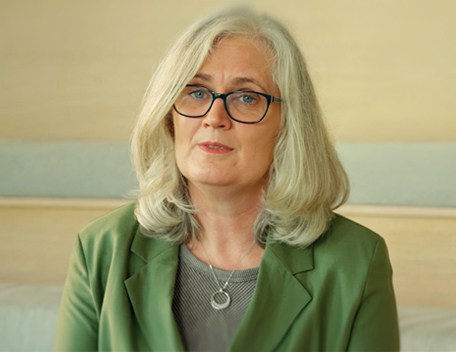 A woman with long blonde hair wearing a green jacket