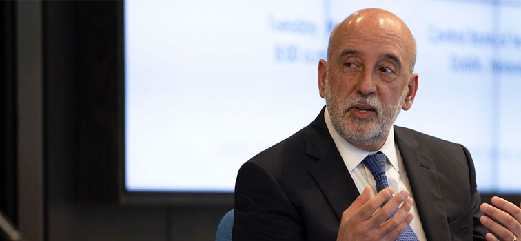 Governor Makhlouf holding his hands up with a lit-up screen in the background