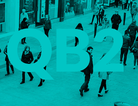 People walking on a street with a green monochrome shade with QB2 written on image